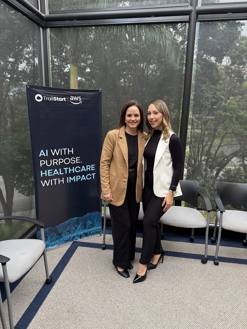 Dos asistentes junto al banner de TrailStart y AWS en el Caracas Health Leaders Summit