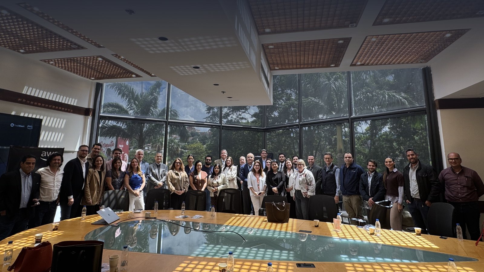 Asistentes del Caracas Health Leaders Summit en la sala de reuniones, junto a los logos de TrailStart y AWS